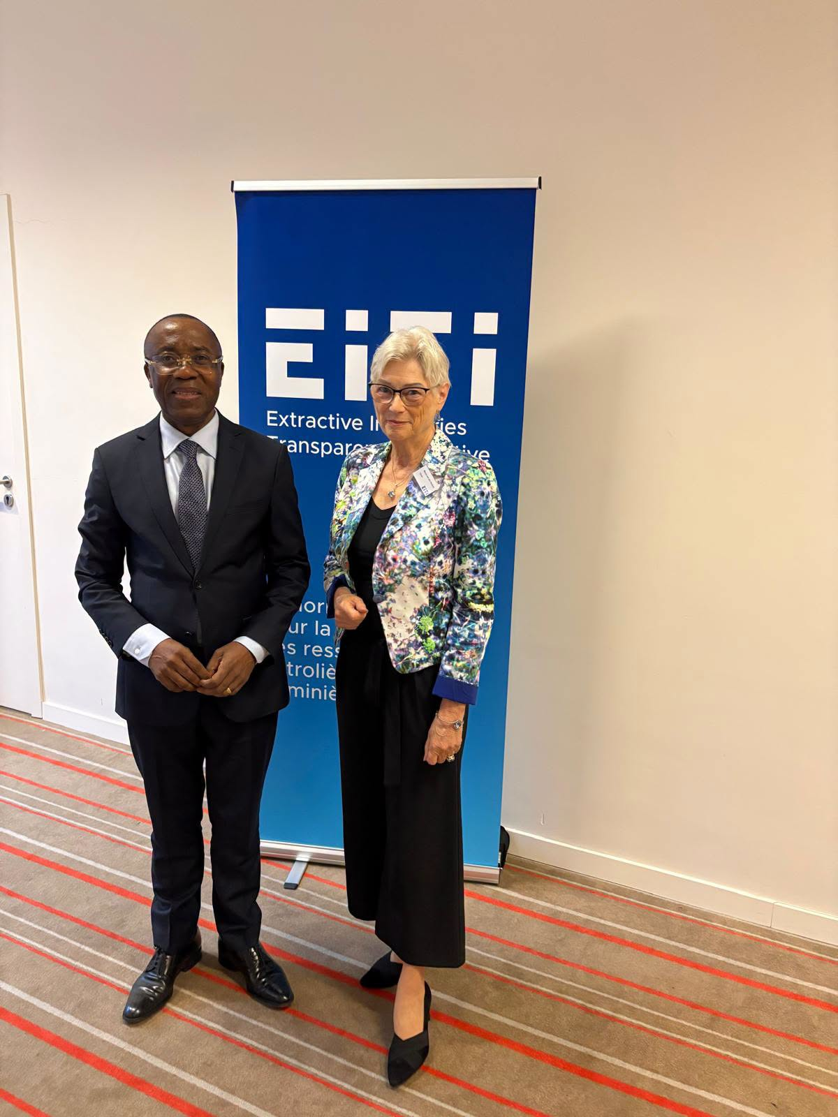 Fuh Calistus Gentry and Maria van der Hoeven standing before an EITI banner